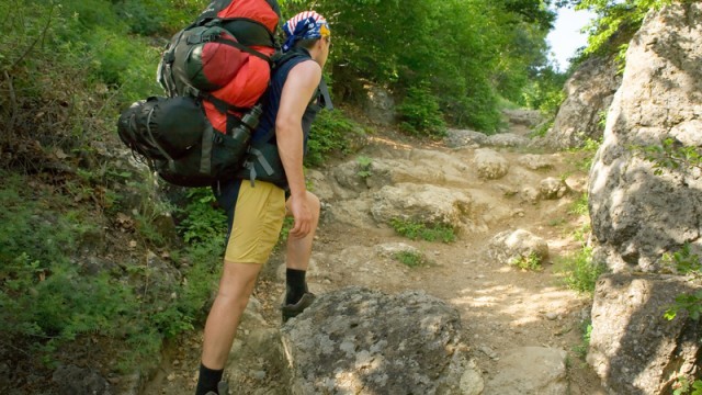 man stepping over rocks while hiking