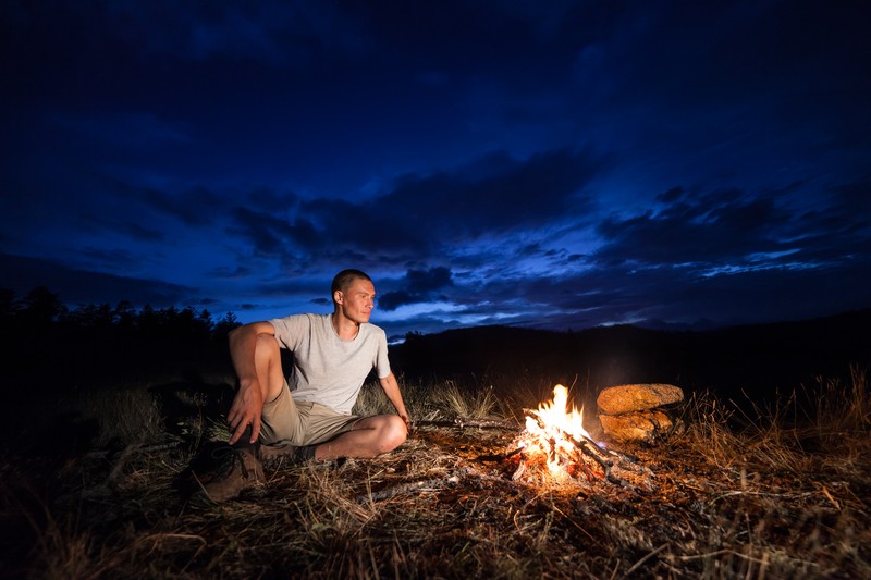 man having a campfire at night