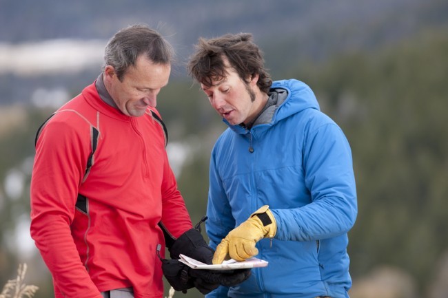two men looking at a map in wilderness