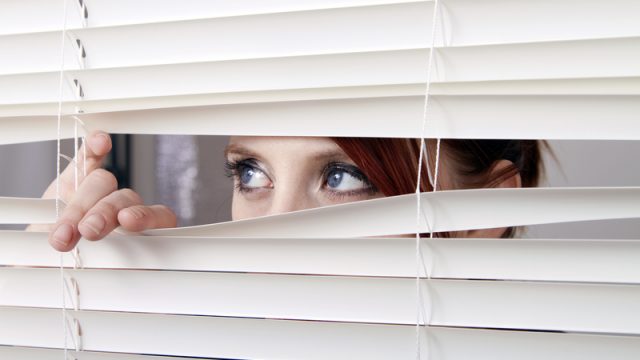 woman looking through blinds