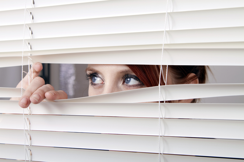 woman looking through blinds