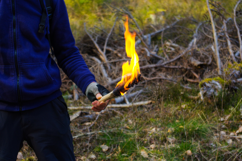 man in the wild with torch flame