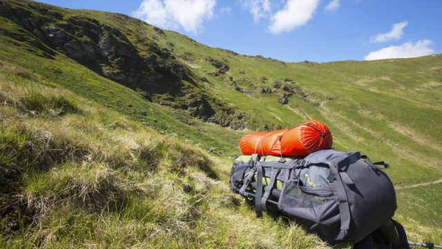 backpack on hill surrounded by mountains