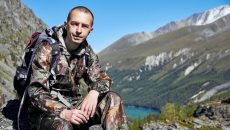 man in camo resting on a mountain