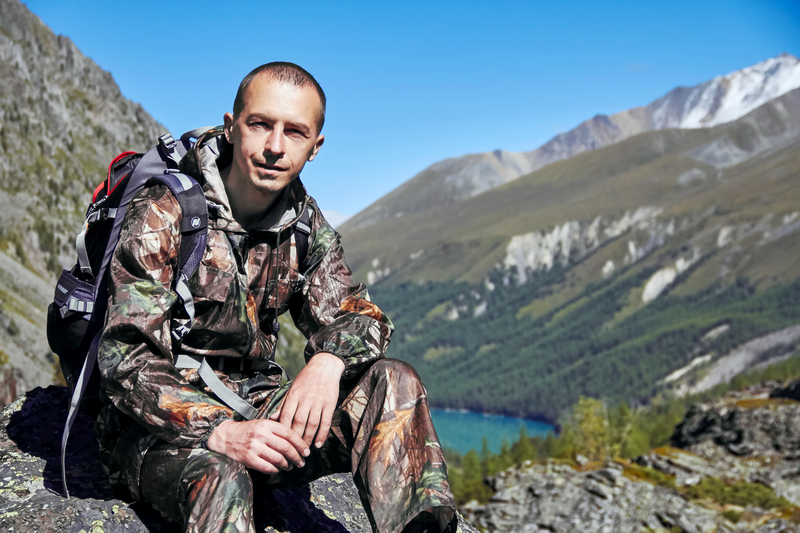 man in camo resting on a mountain